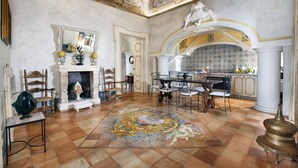 A spacious room with a fireplace, a dining area, and a kitchen with a tiled backsplash. - Residenza Crocione - Terrace sea view (Positano)