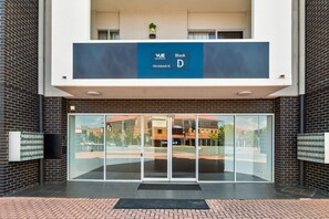 A modern building entrance with a glass door, a sign indicating 'VUE Residences, Block D, 150 Anketell St.' - Bright 1-bed Apartment in Greenway (Canberra)