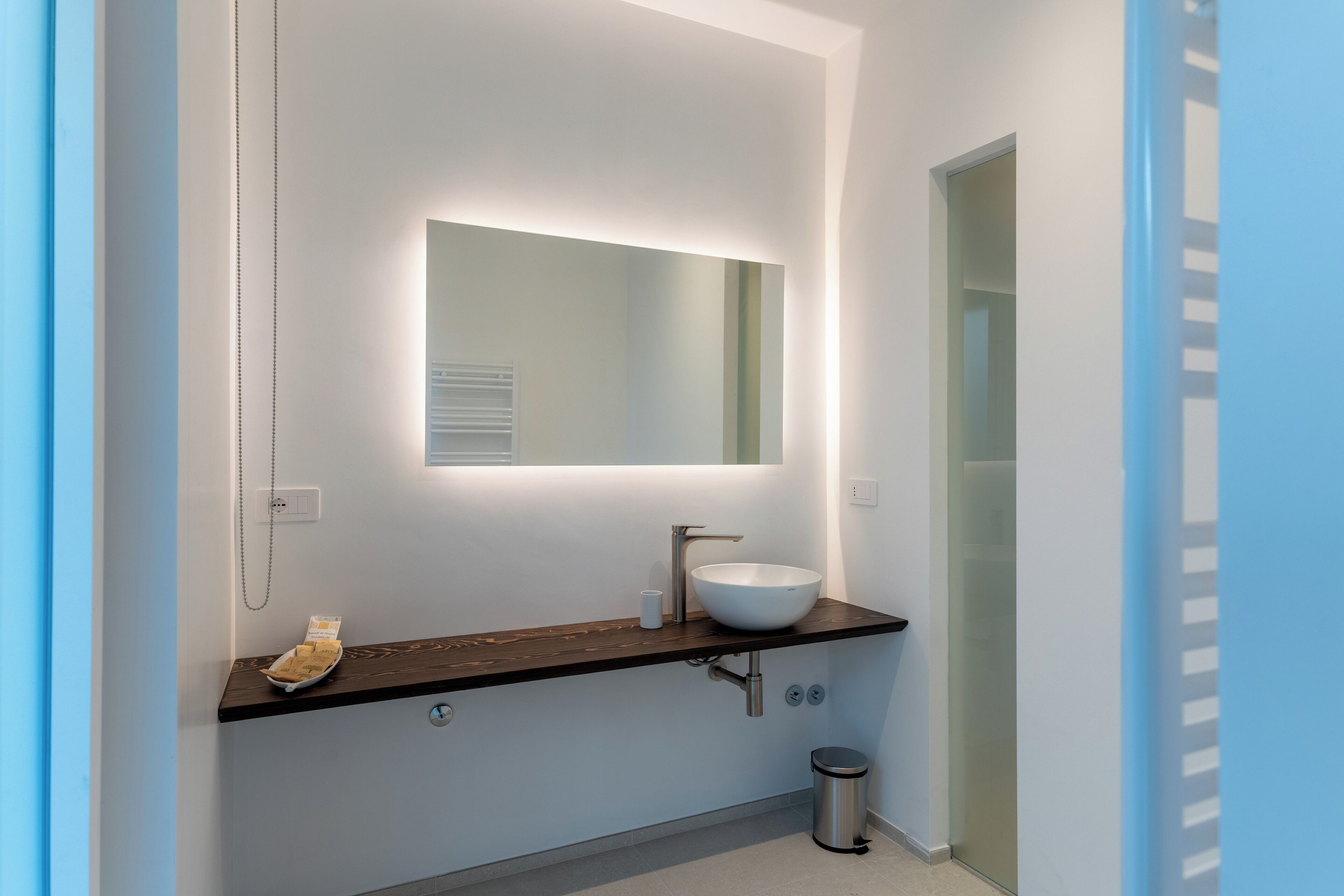 A modern bathroom with a white sink, dark countertop, and a mirror above it.