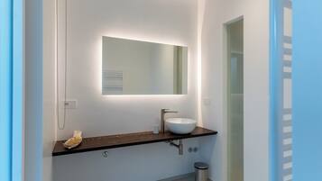 A modern bathroom with a white sink, dark countertop, and a mirror above it.