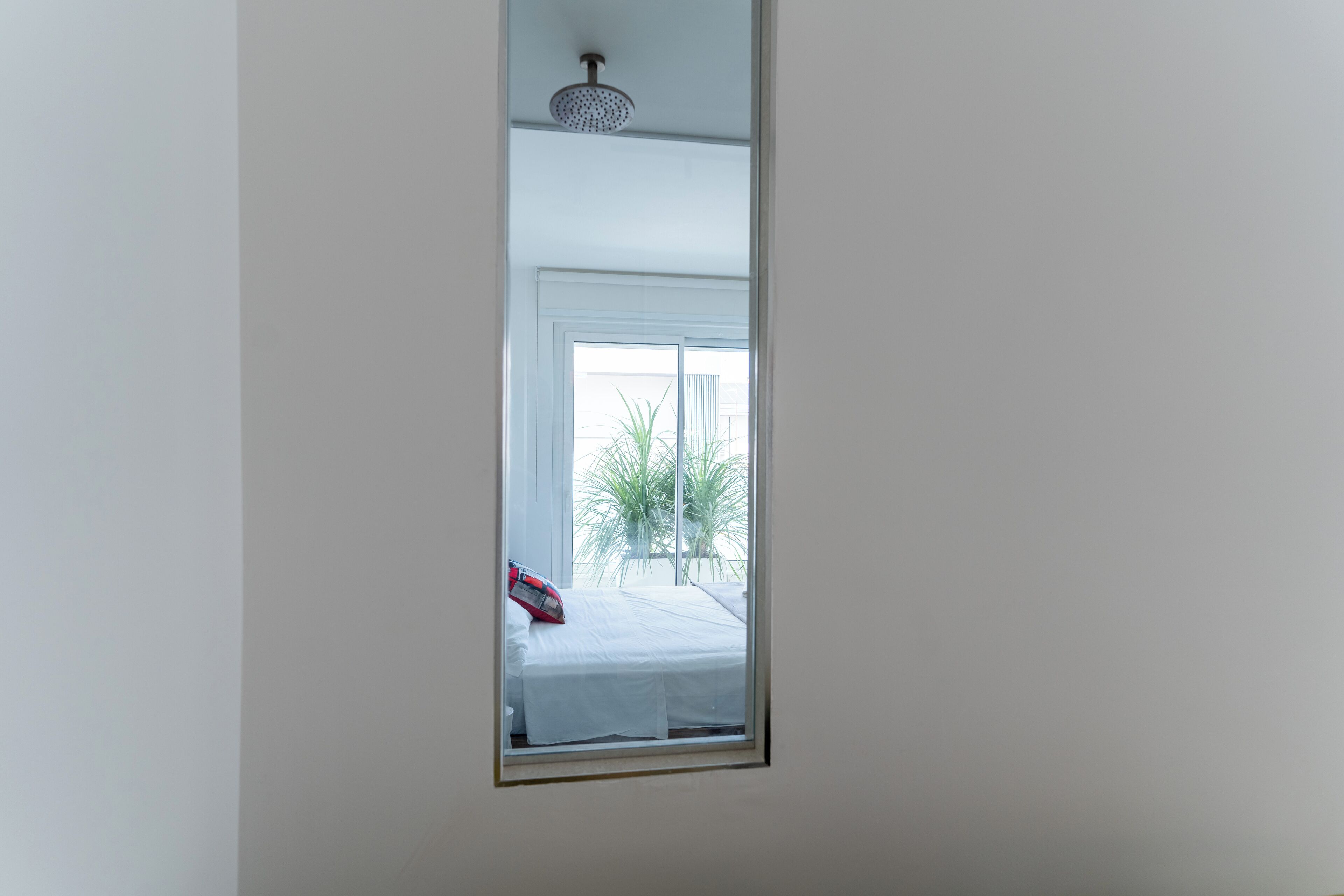 Quarto com cama, janela e chuveiro no teto.