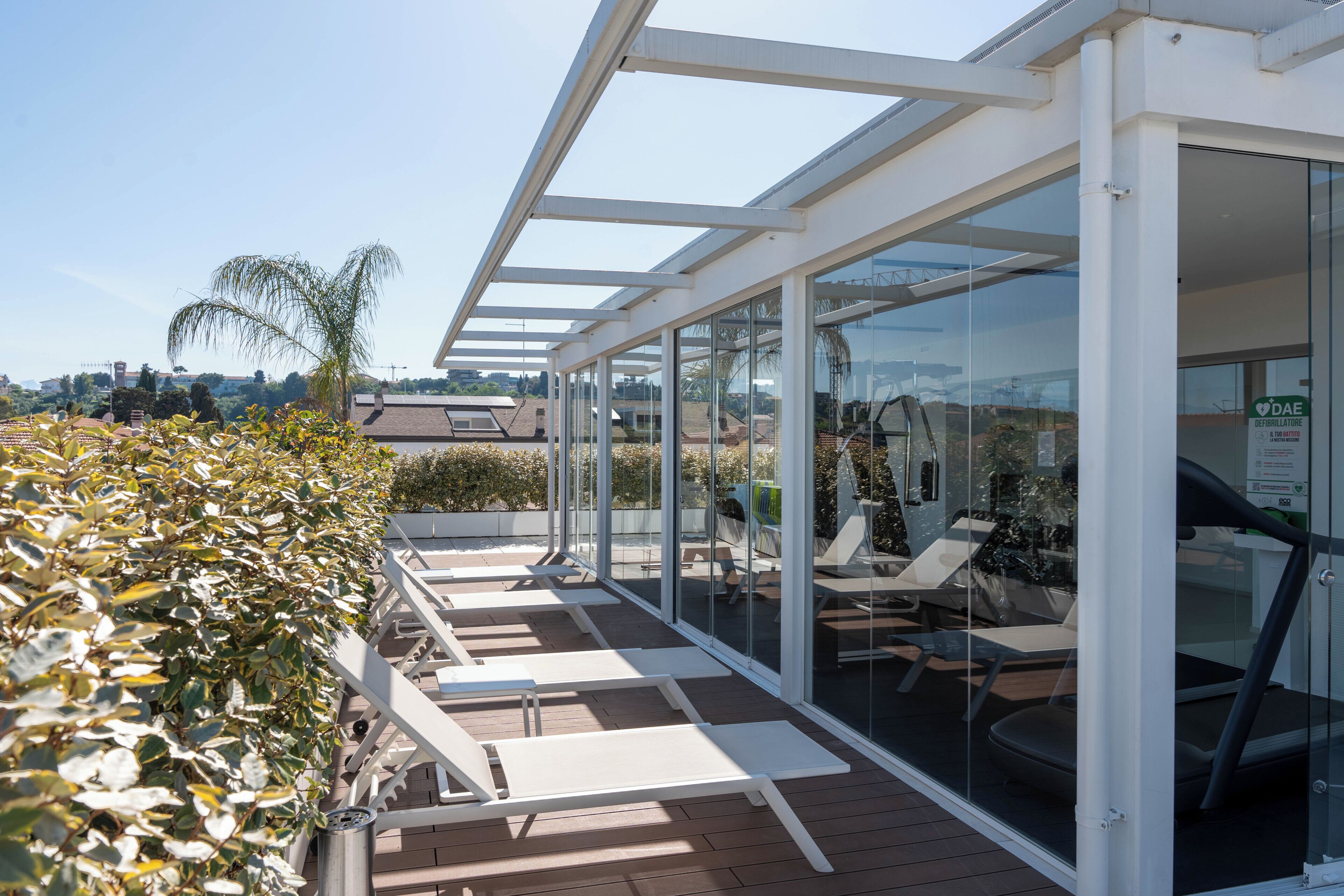 A covered outdoor area with glass walls, seating, and a view of the surrounding landscape.