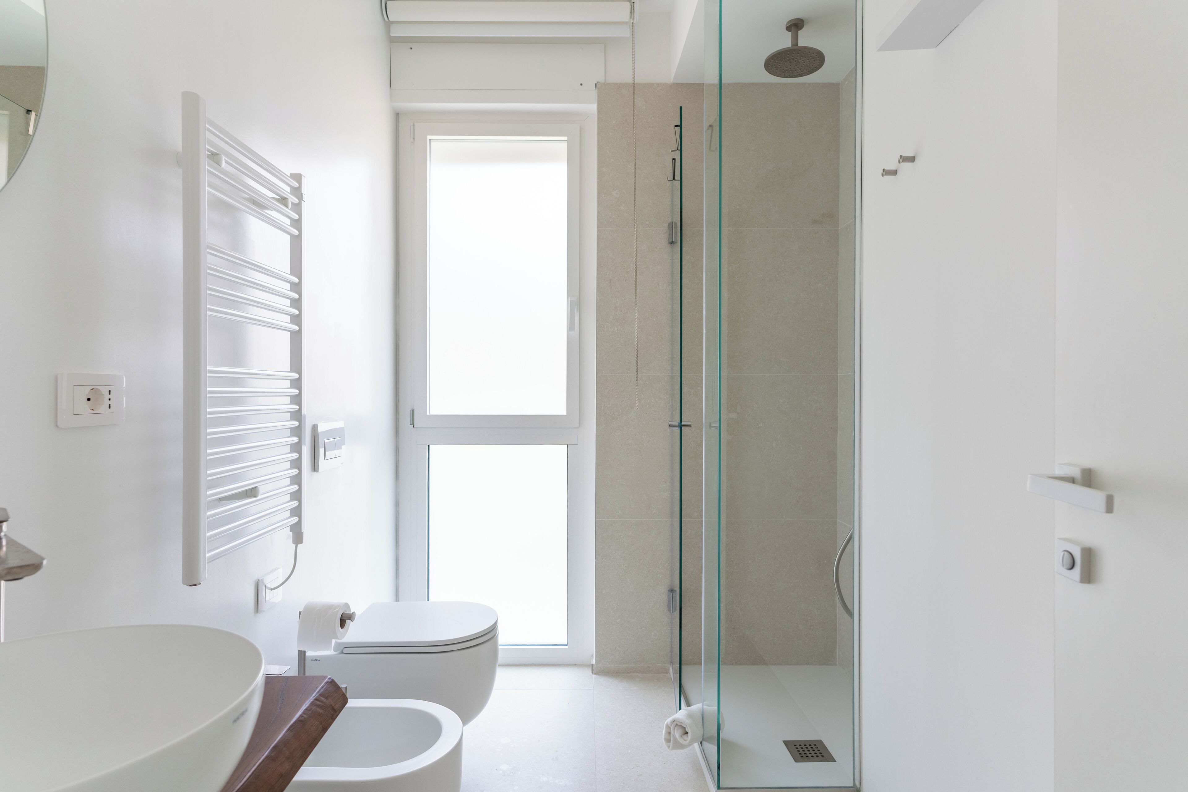 Une salle de bain moderne avec une douche à parois de verre, un lavabo blanc et des toilettes.