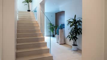 A modern interior with a staircase, potted plants, and minimalist decor.