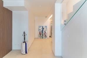 A modern hallway with a wooden floor, a glass railing, and a painting on the wall.