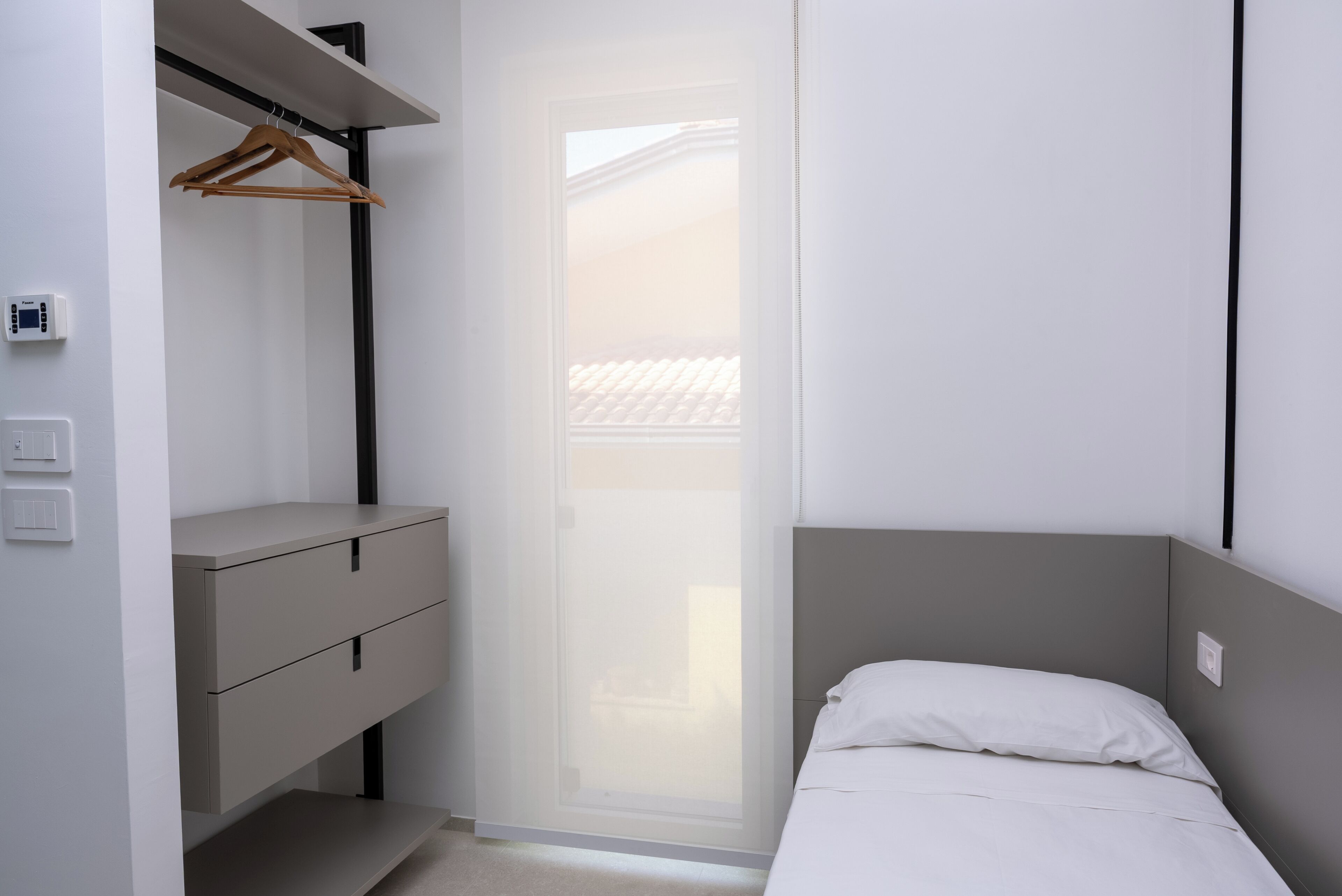 A bedroom with a bed, a wardrobe, and a window.