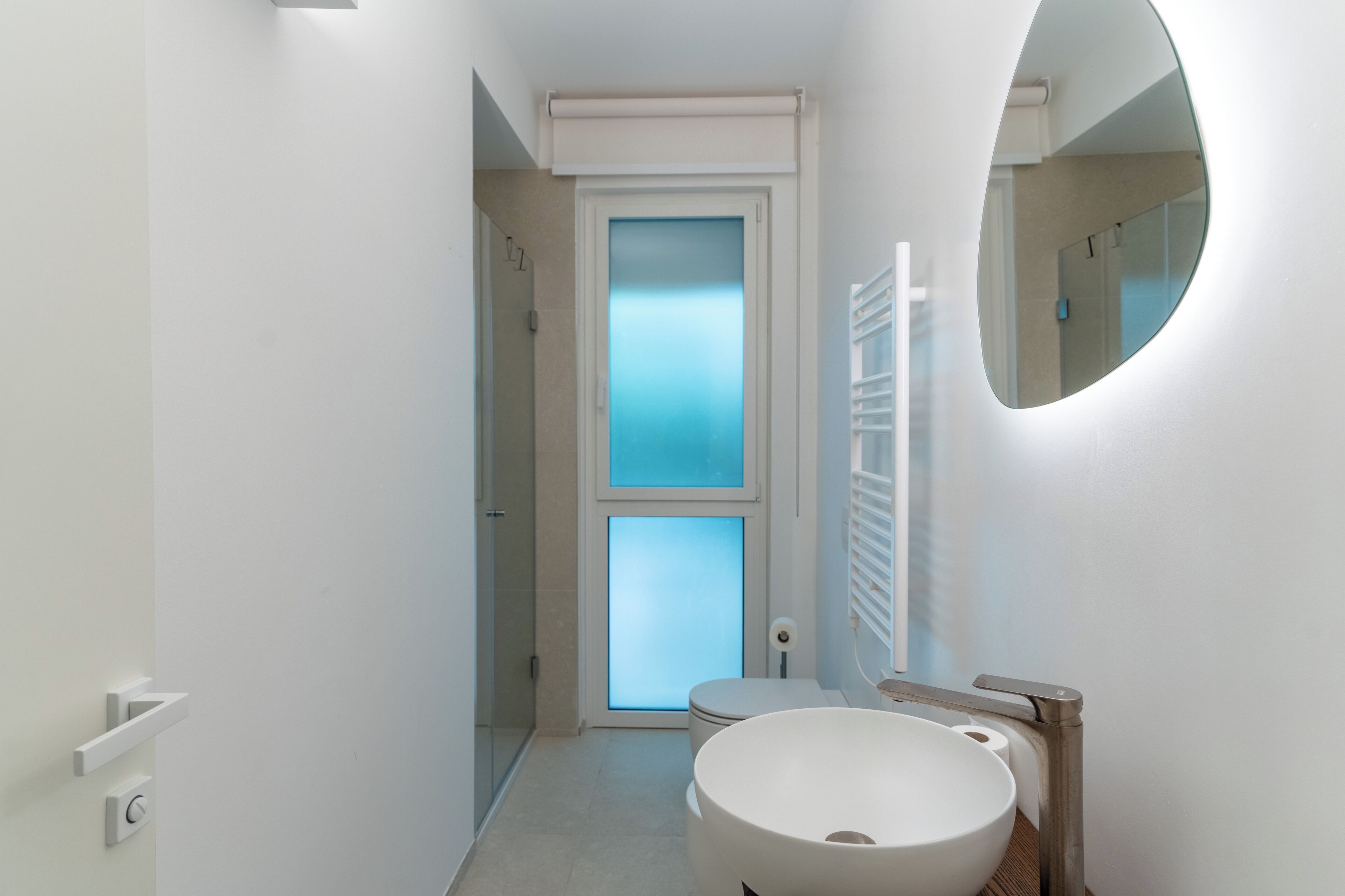 Ein modernes Badezimmer mit einem runden Waschbecken, einer Toilette und einer Milchglasschiebetür.