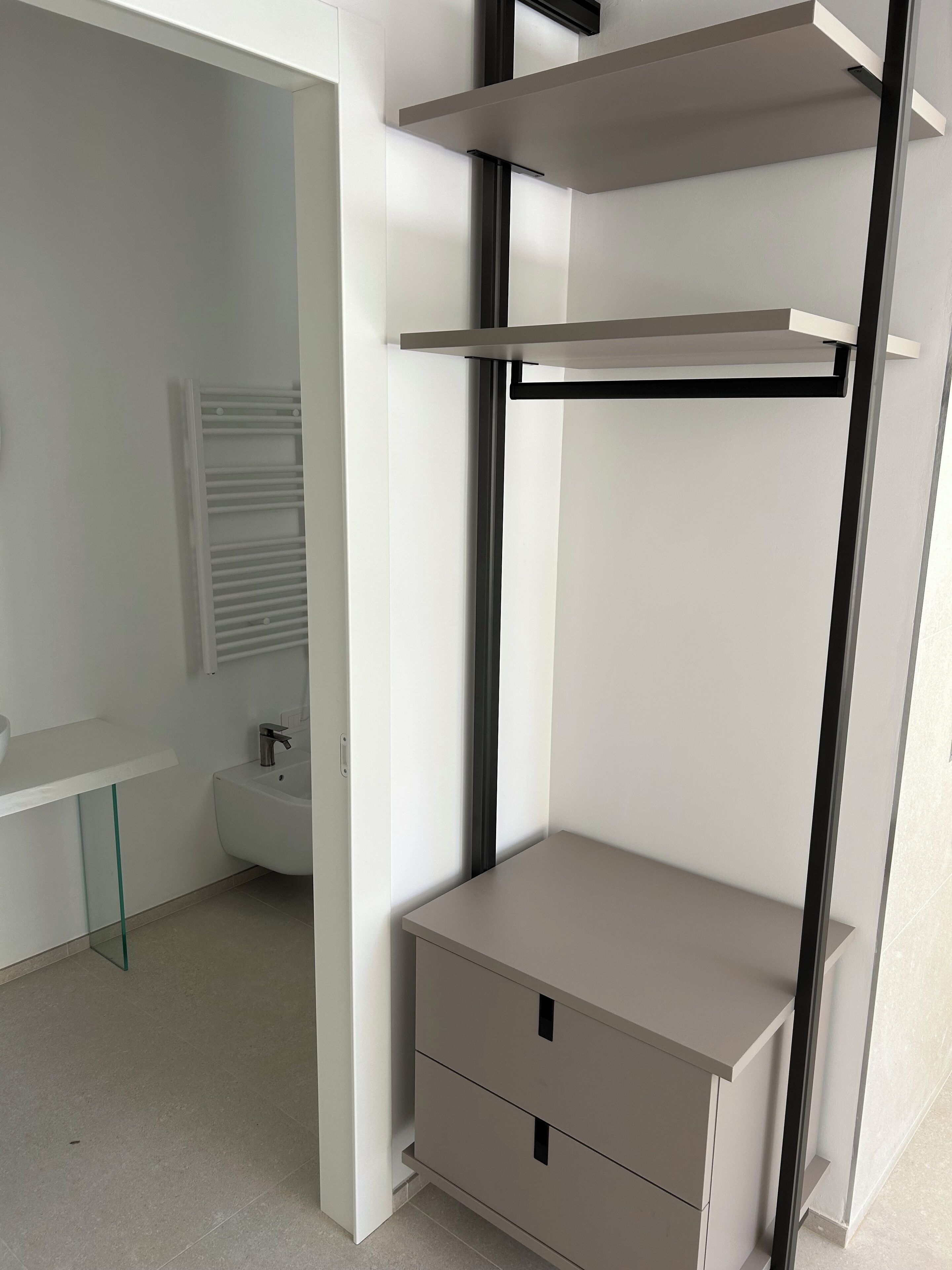 Ein modernes, minimalistisches Badezimmer mit einem weißen Waschbecken, einem Bidet und einem Glasvitrinen-Schrank.