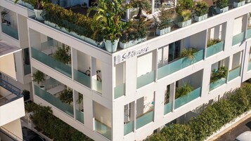 Ένα πολυώροφο κτίριο με μπαλκόνια, γλάστρες με φυτά και μια επιγραφή που γράφει «Sublimart».