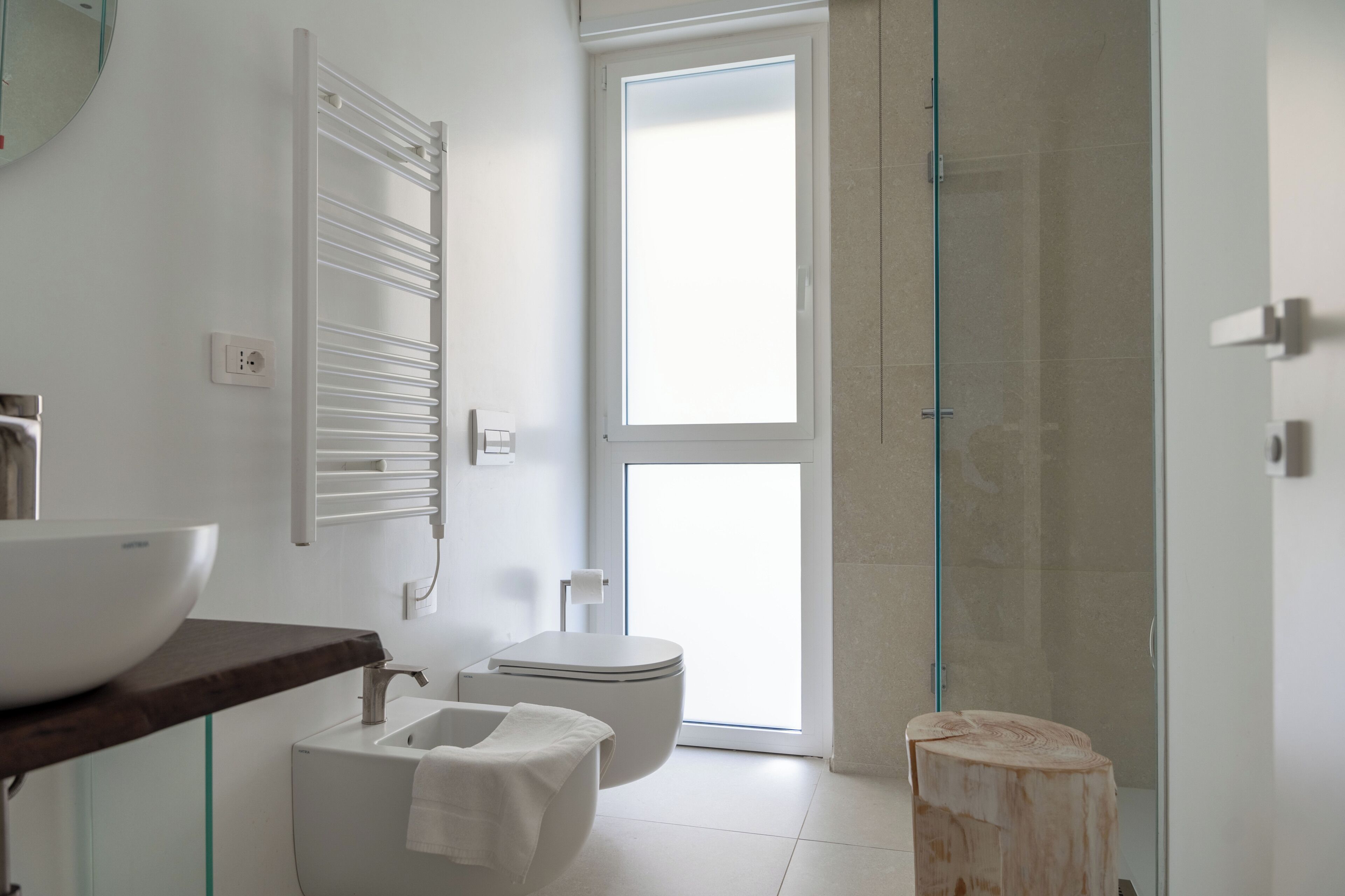 Un bagno moderno con un lavandino ampio, un water e un box doccia in vetro.