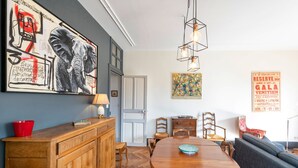 Ein Essbereich mit Holztisch, Stühlen, einer Couch und einem Gemälde an der Wand.