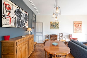 Un comedor con una mesa de madera, sillas, un sofá y un cuadro en la pared.