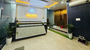 A hotel reception area with a marble reception desk, a chandelier, and a sign that reads "The Grand Palace." - THE GRAND PALACE (Prayagraj)