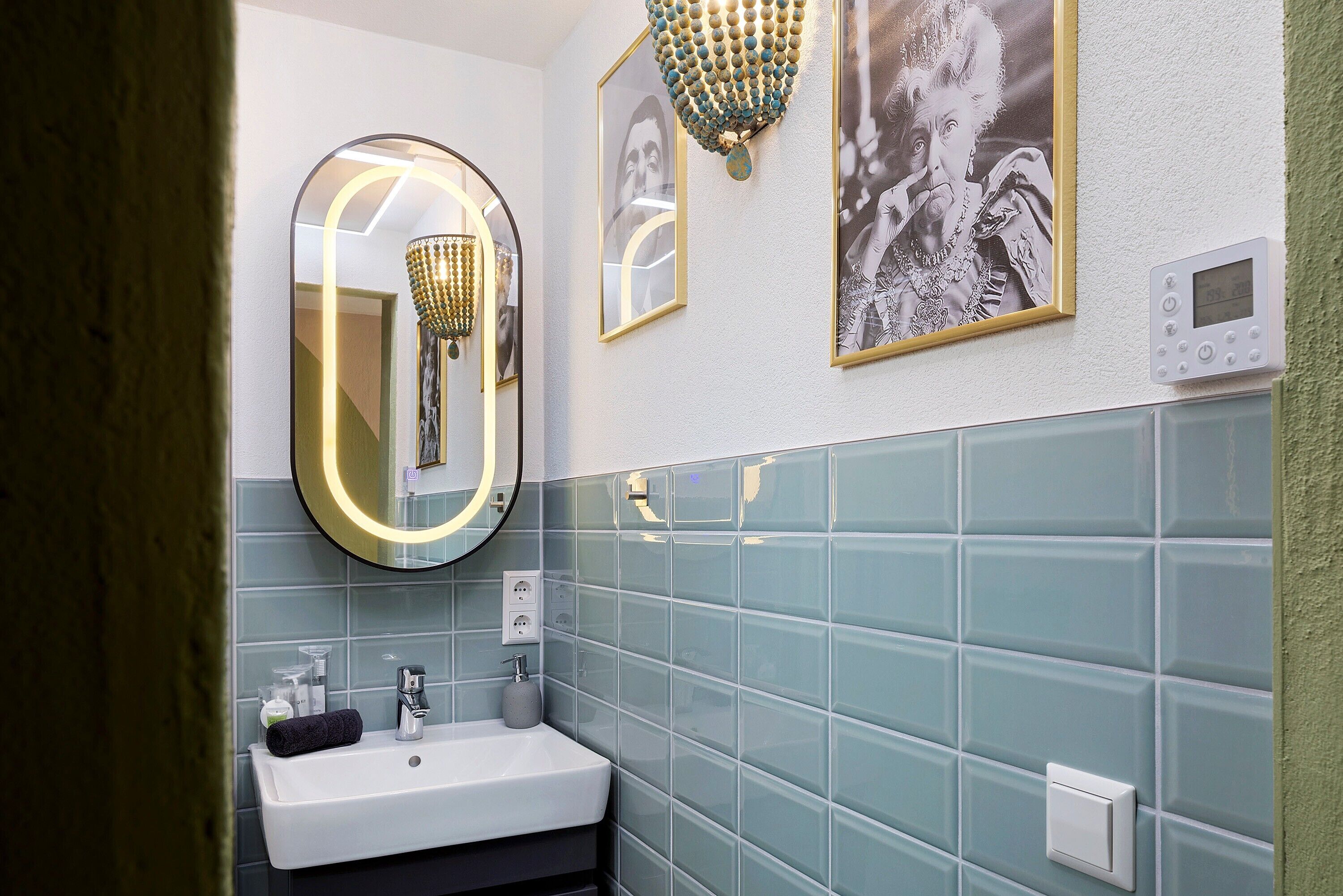 Ein Badezimmer mit einem weißen Waschbecken, einem Spiegel mit Beleuchtung und einer Wandleuchte.