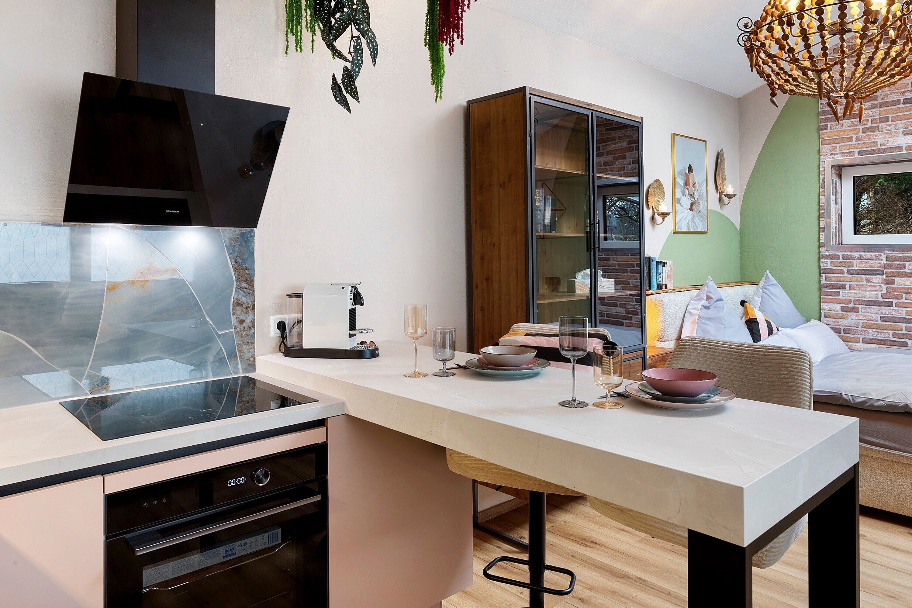 A modern kitchen with a built-in oven, a dining area with a table and chairs, and a brick wall.