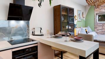 A modern kitchen with a built-in oven, a dining area with a table and chairs, and a brick wall.