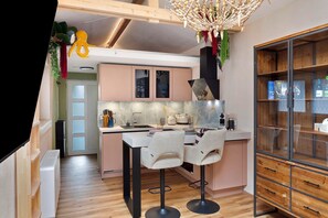 Eine moderne Küche mit einer zentralen Kochinsel, Barhocker und einem Holzkasten mit Glastüren.