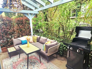 Eine Terrasse im Freien mit einer Couch, einem Tisch und einem Grill.