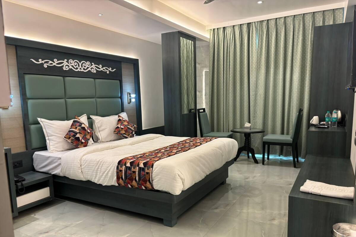 Een moderne hotelkamer met een groot bed, een nachtkastje, een stoel, een klein rond tafeltje en een badgedeelte.