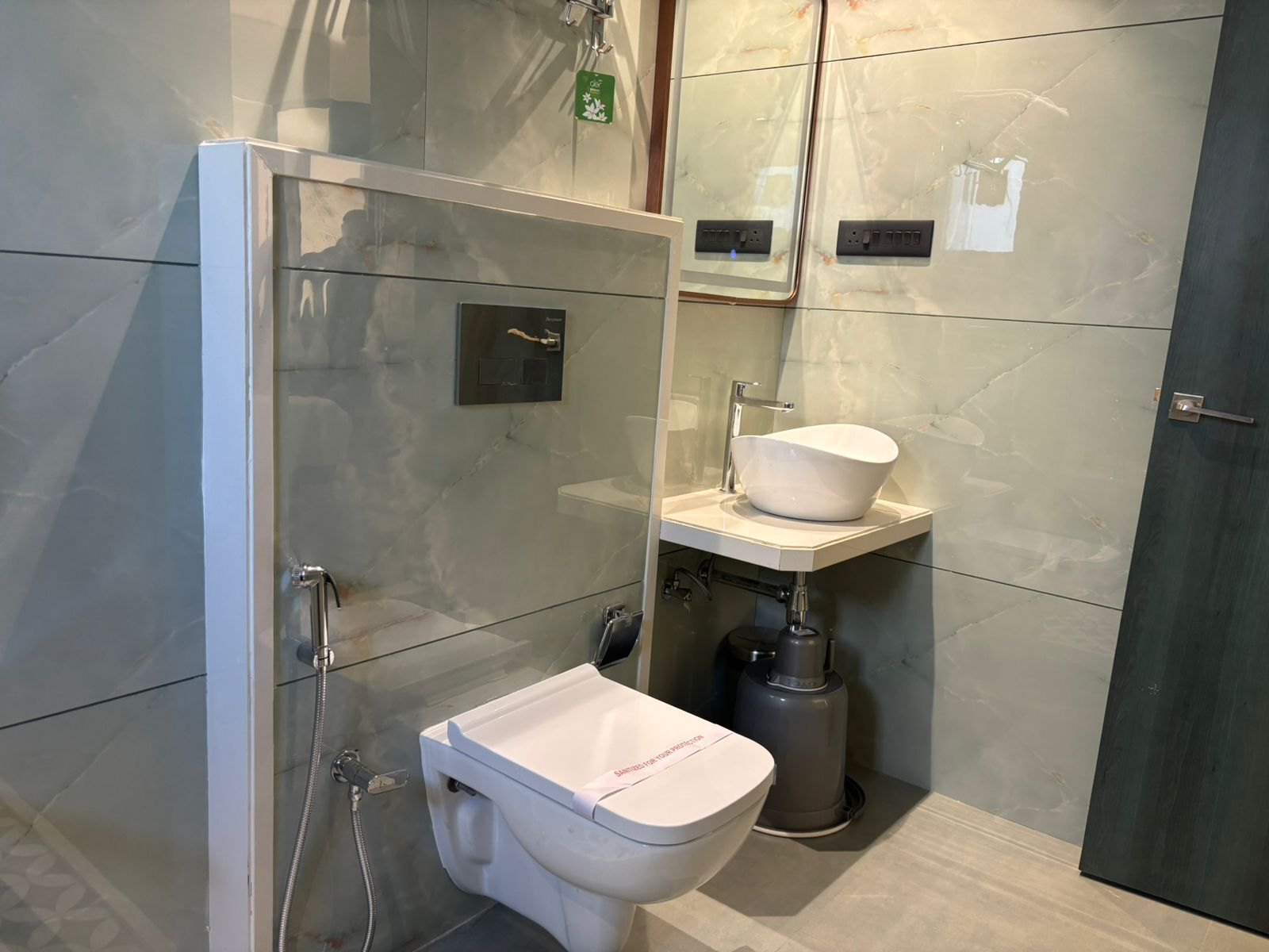 Une salle de bain moderne avec une douche à parois de verre, des toilettes blanches et un lavabo sur colonne.