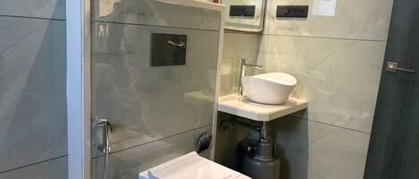 A modern bathroom with a glass-enclosed shower, a white toilet, and a pedestal sink.
