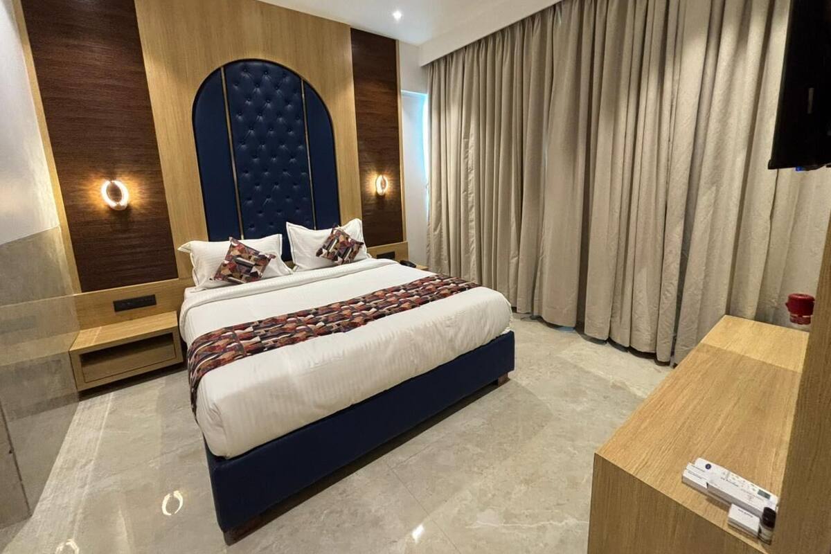 Een moderne hotelkamer met een groot bed, houten lambrisering, een plafondventilator en een groot raam met gordijnen.