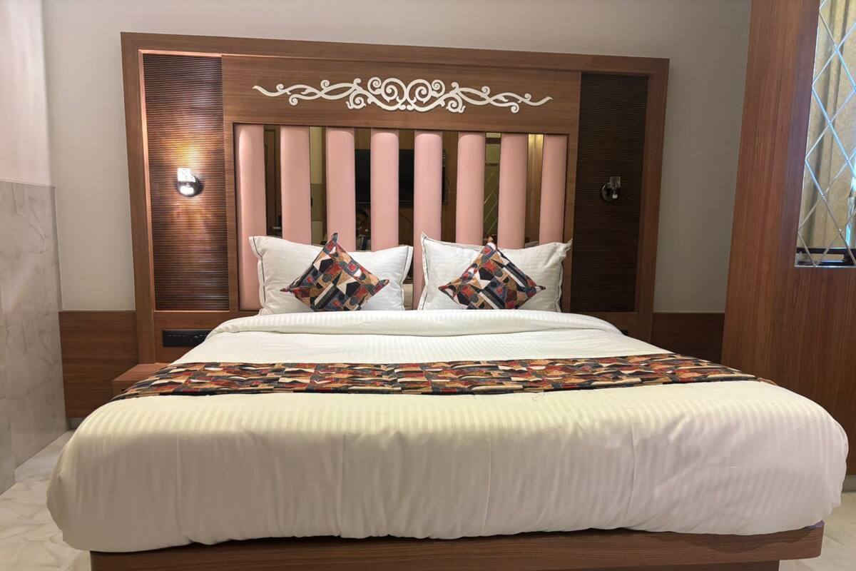 Een bed met een houten hoofdbord, wit beddengoed en decoratieve kussens.