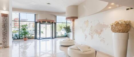 Un hall d’entrée spacieux agrémenté d’une fresque représentant une carte du monde, d’un comptoir d’accueil et de plusieurs espaces détente.