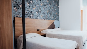 A modern hotel room with two single beds, a wooden headboard, and a floral-patterned wall. - HOTEL ACQUARIO (Marina di Vasto)
