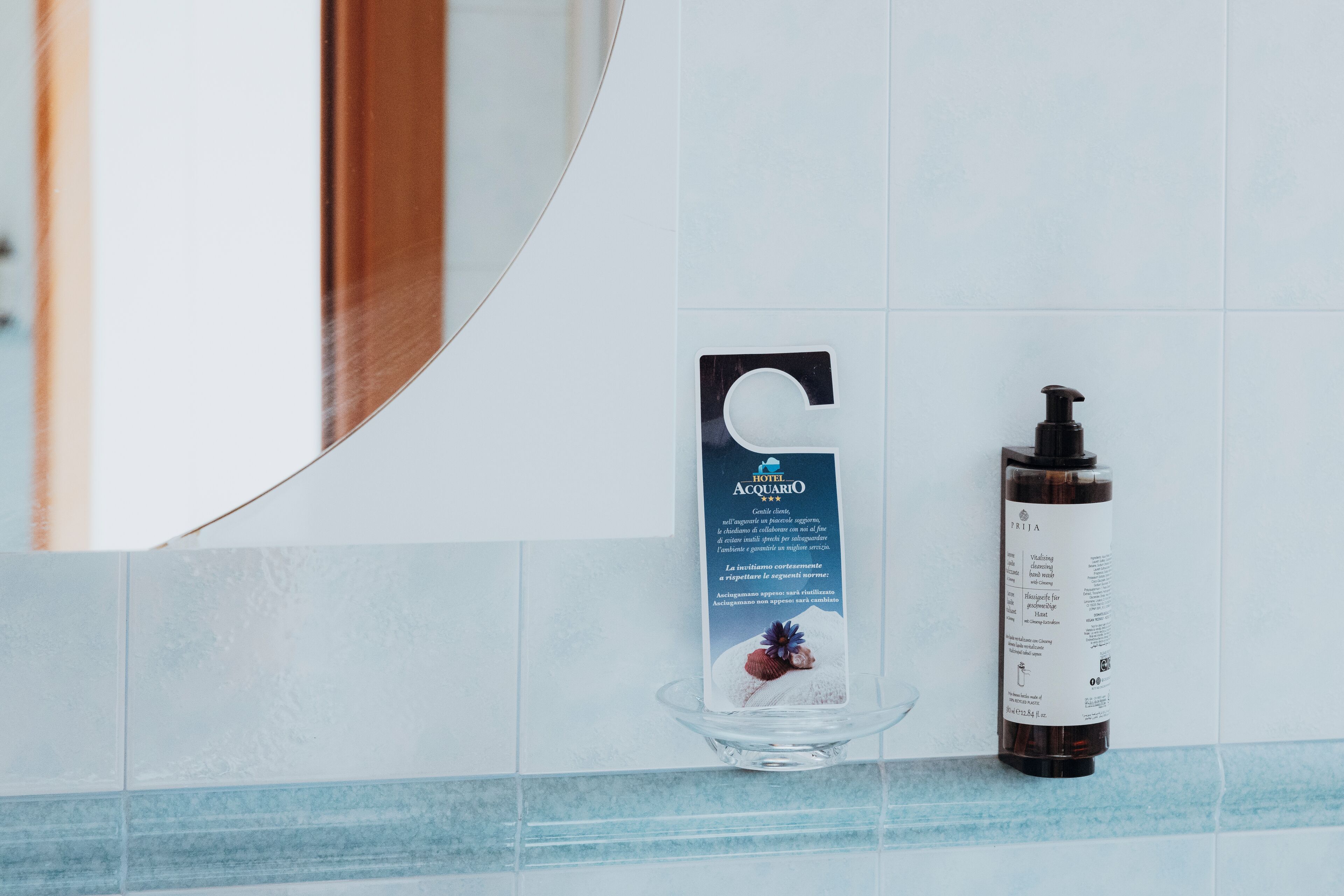 Ein Badezimmer mit weiß-blauen Fliesen, einer Seifenschale aus Glas und einer Flasche Flüssigseife.