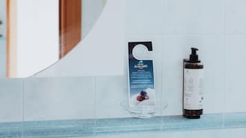 Un baño con pared de azulejos blancos y azules, un jabonera de vidrio y una botella de jabón líquido.