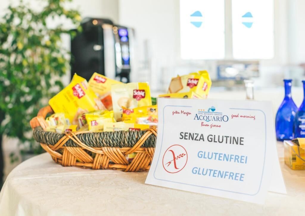 A table with a gluten-free sign, a wicker basket of snacks, and a coffee machine in the background.
