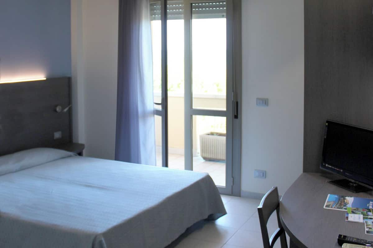 A hotel room with a bed, a desk, and a television.