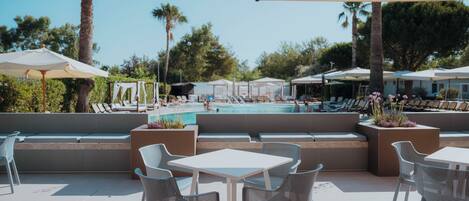 An outdoor seating area with a pool view, including lounge chairs and umbrellas.
