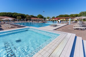 Ein Schwimmbecken mit mehreren Bahnen, Liegestühlen und Sonnenschirmen.