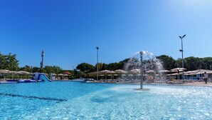 A swimming pool with a water fountain, umbrellas, and lounge chairs. - Club del Sole Le Gorette Cecina Easy Camping Village (Cecina)