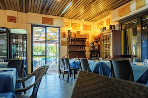 An indoor restaurant with tables and chairs, a wine display, and a view of the outside.