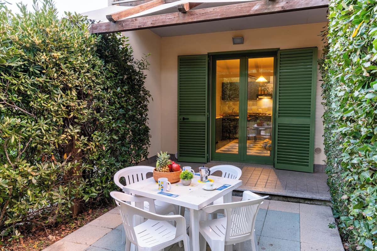 Un patio con una mesa, sillas, una cesta de fruta y una planta en maceta.