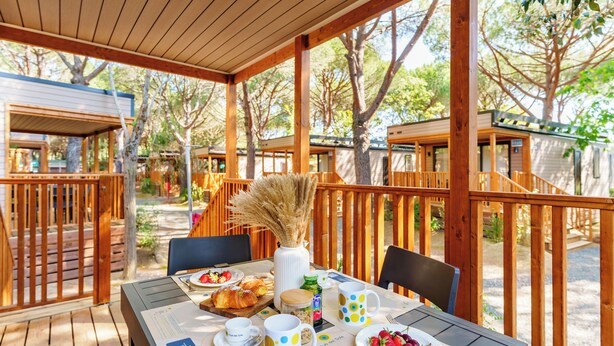 An outdoor dining area with wooden tables, chairs, and a pergola. - Club del Sole Le Gorette Cecina Easy Camping Village (Cecina)