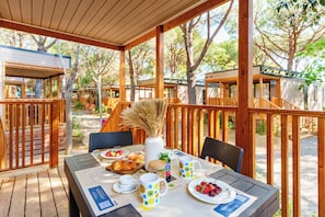 Ein Essbereich im Freien mit Holztischen, -stühlen und einer Pergola.