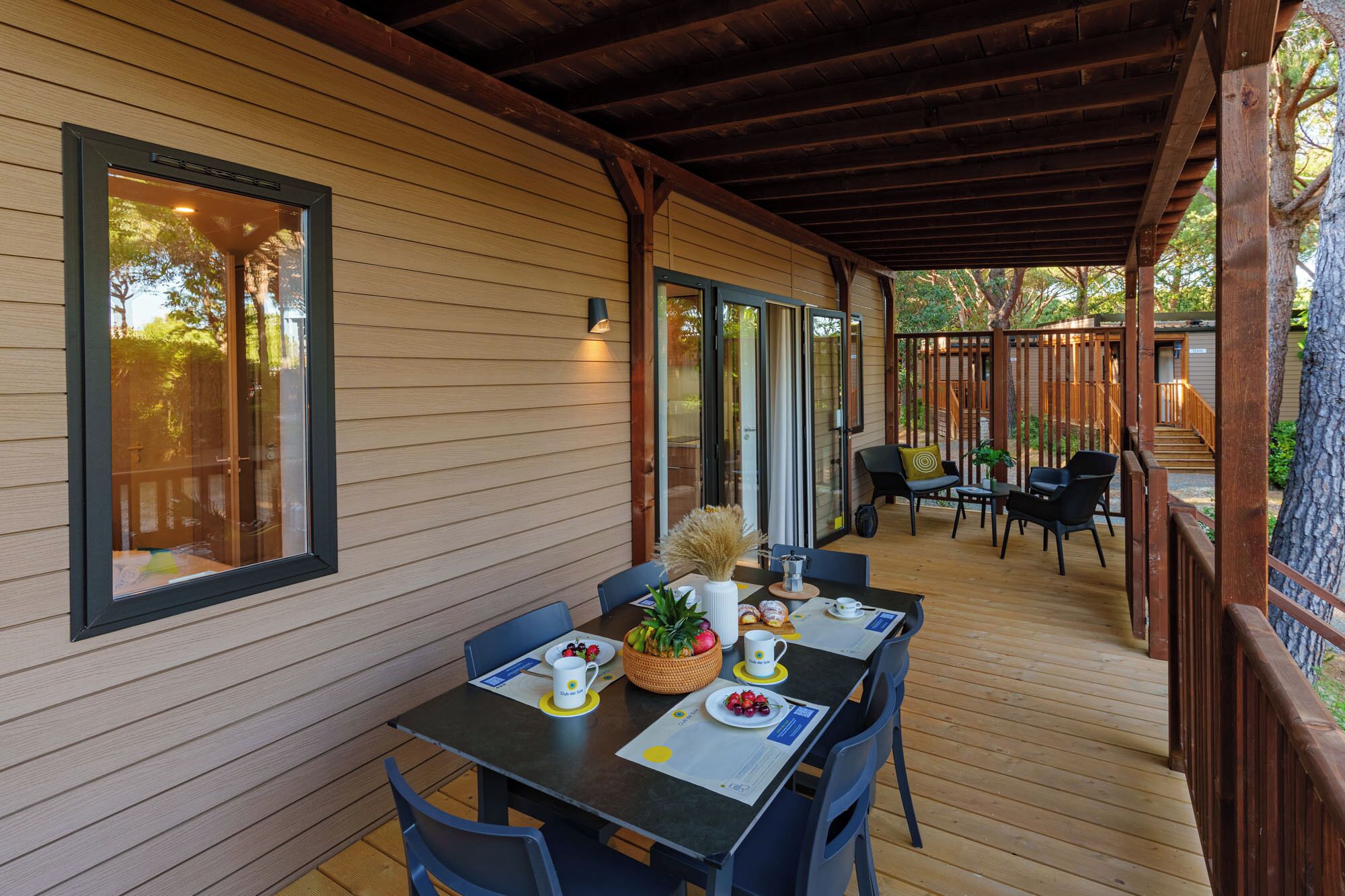 A covered outdoor dining area with wooden walls and a wooden deck.