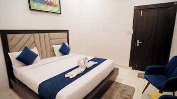 A hotel room with a bed, a chair, a door, and a painting on the wall.