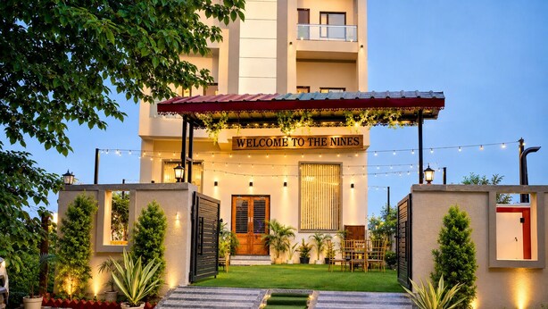 A hotel entrance with a welcoming sign, a covered entrance area, and a well-maintained lawn. - The Nines Hotel & Restro (Haldwani)