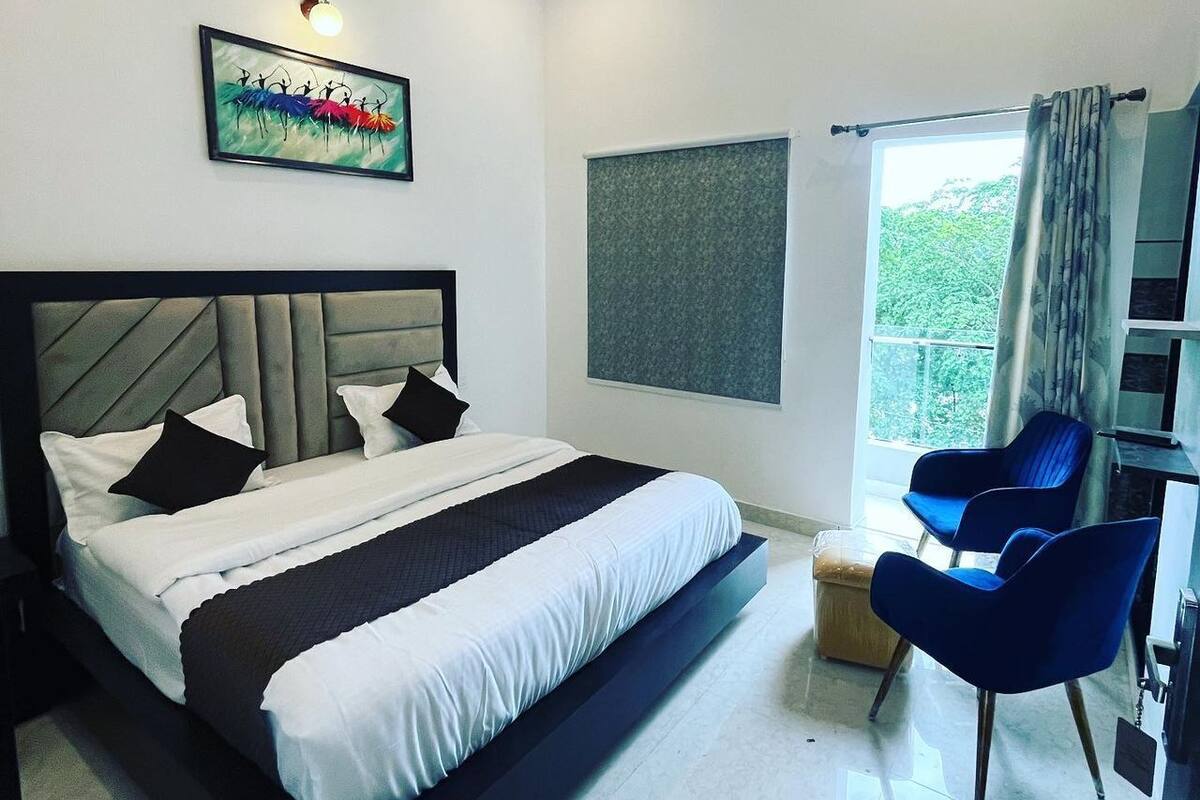 Un dormitorio moderno con una cama grande, un ventilador de techo, una ventana con cortinas y un cuadro en la pared.