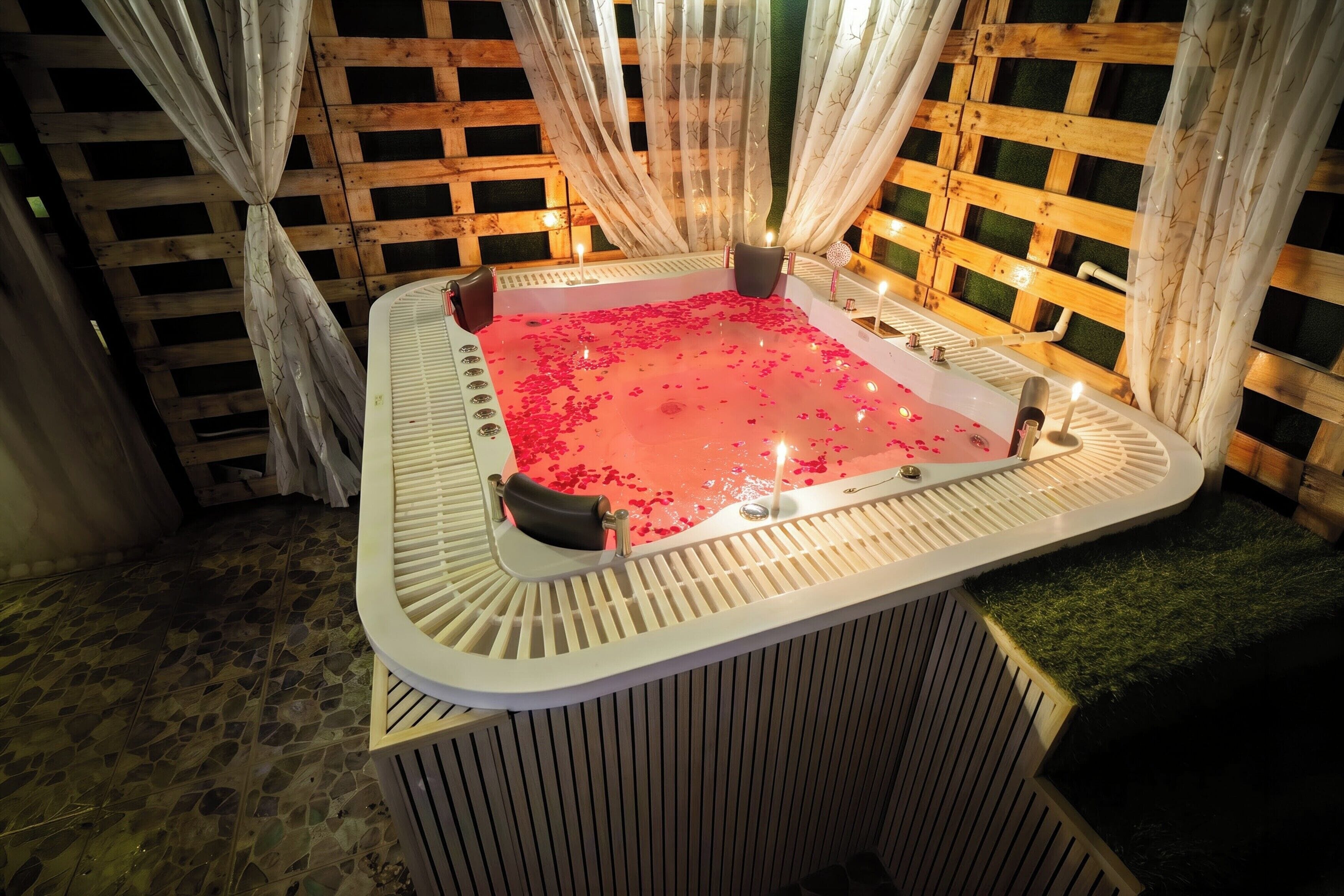 Zona de spa con un jacuzzi rodeado de paneles de madera y cortinas translúcidas.