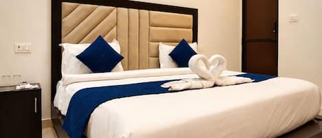 A hotel room with a large bed, a headboard, a nightstand, and a painting on the wall.