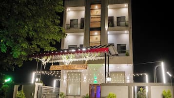 A multi-story hotel with a well-lit entrance, a visible reception area, and a sign indicating the hotel's name.