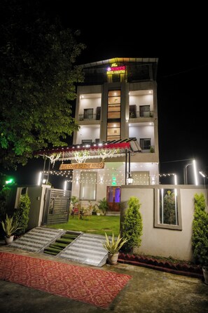 A multi-story hotel with a well-lit entrance, a visible reception area, and a sign indicating the hotel's name. - The Nines Hotel & Restro (Haldwani)