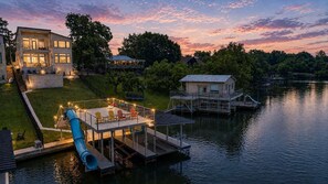 A lakeside property with a dock, a slide, and a deck with outdoor seating.