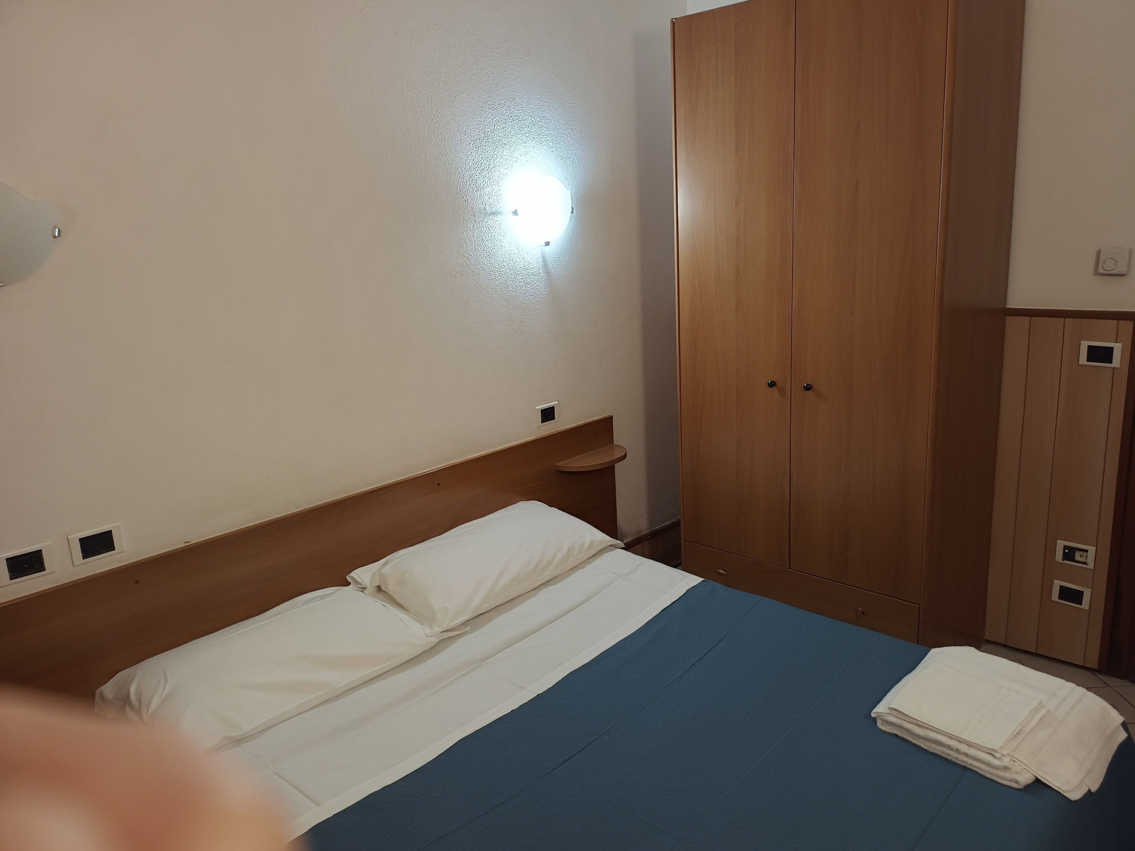 A bedroom with a bed, a wardrobe, and a nightstand.